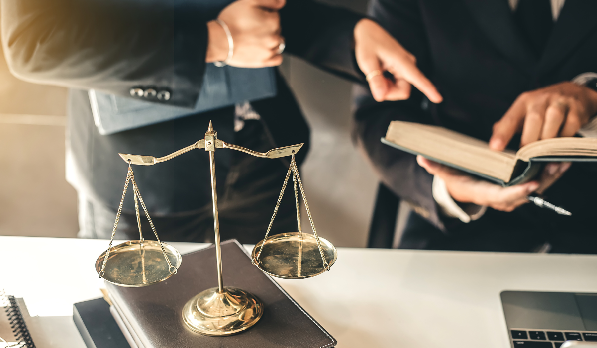 A lawyer and a legal translator dressed in business attire consult a law book to help with legal document translation.