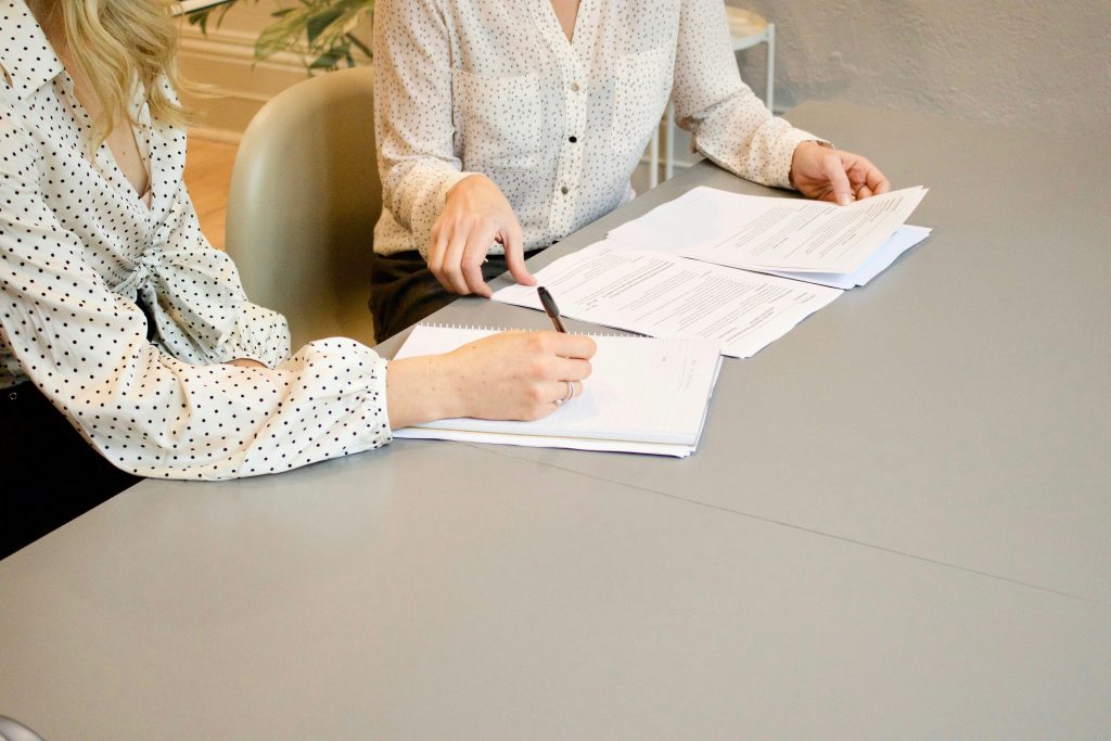A lawyer and an interpreter in polka dot shirts are seated at a table reviewing documents and taking notes.